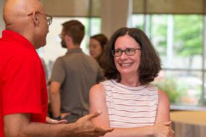 A man in a red shirt talks with a woman in a striped shirt